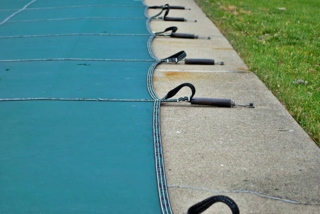 backyard swimming pool with diving board and pool slide tarped up and closed down for winter